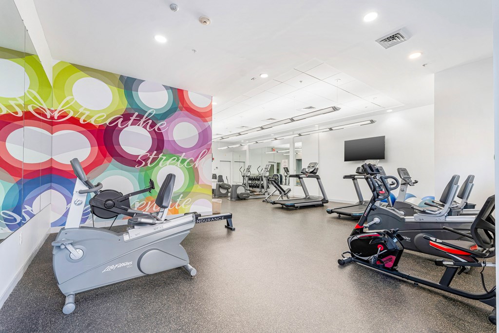 A gym with a row of exercise bikes and a television.