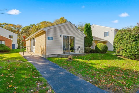 A house numbered 123 is surrounded by a grassy area with fallen leaves.