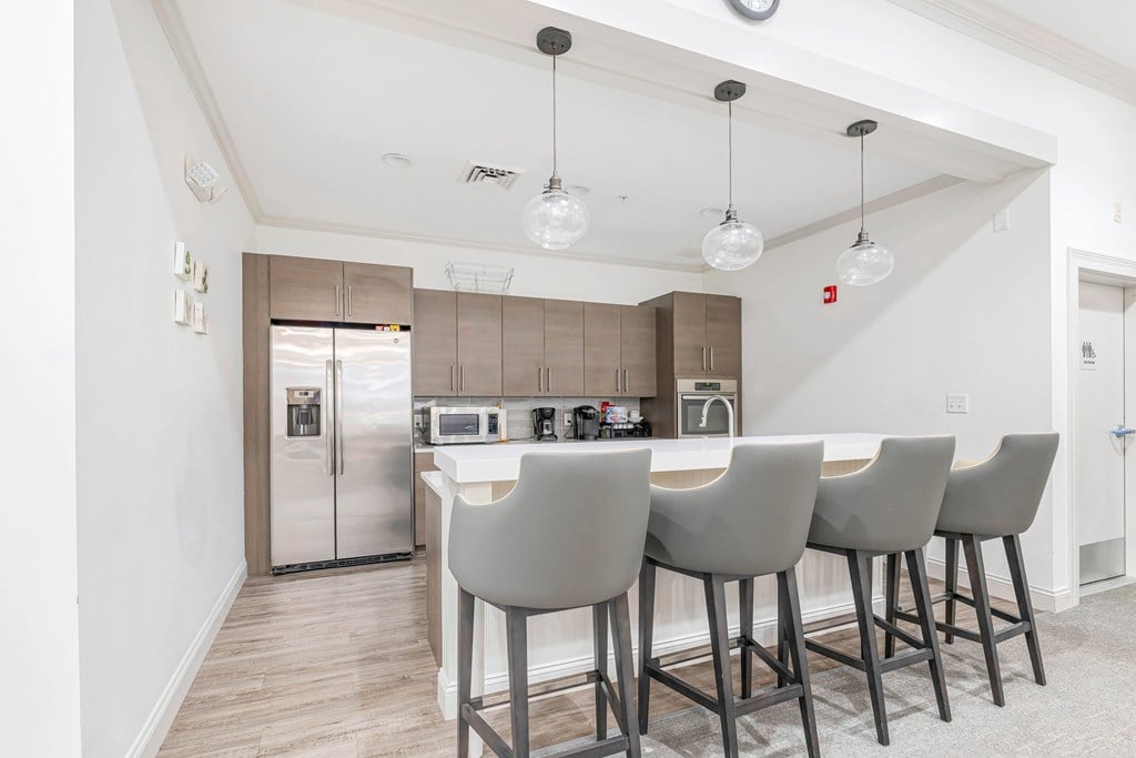 A kitchen with a bar area and grey chairs.