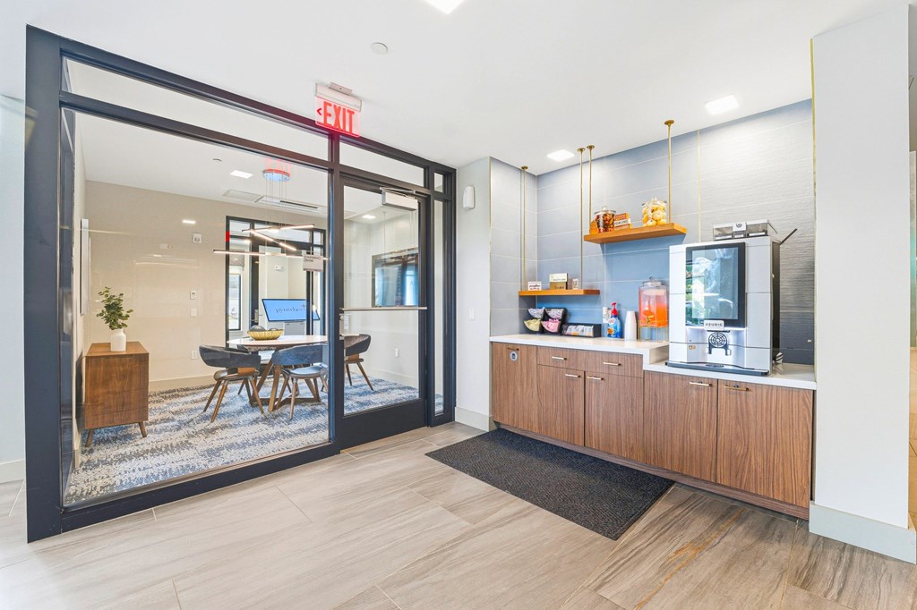 A modern office space with a glass door entrance and a kitchenette area.