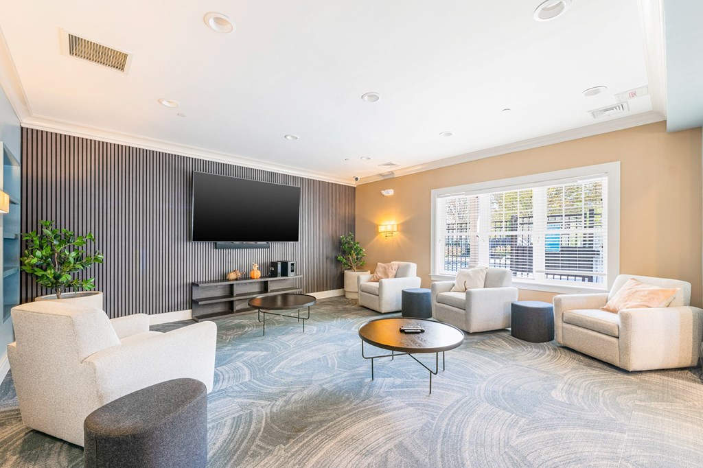 A living room with a grey carpet and a large window.
