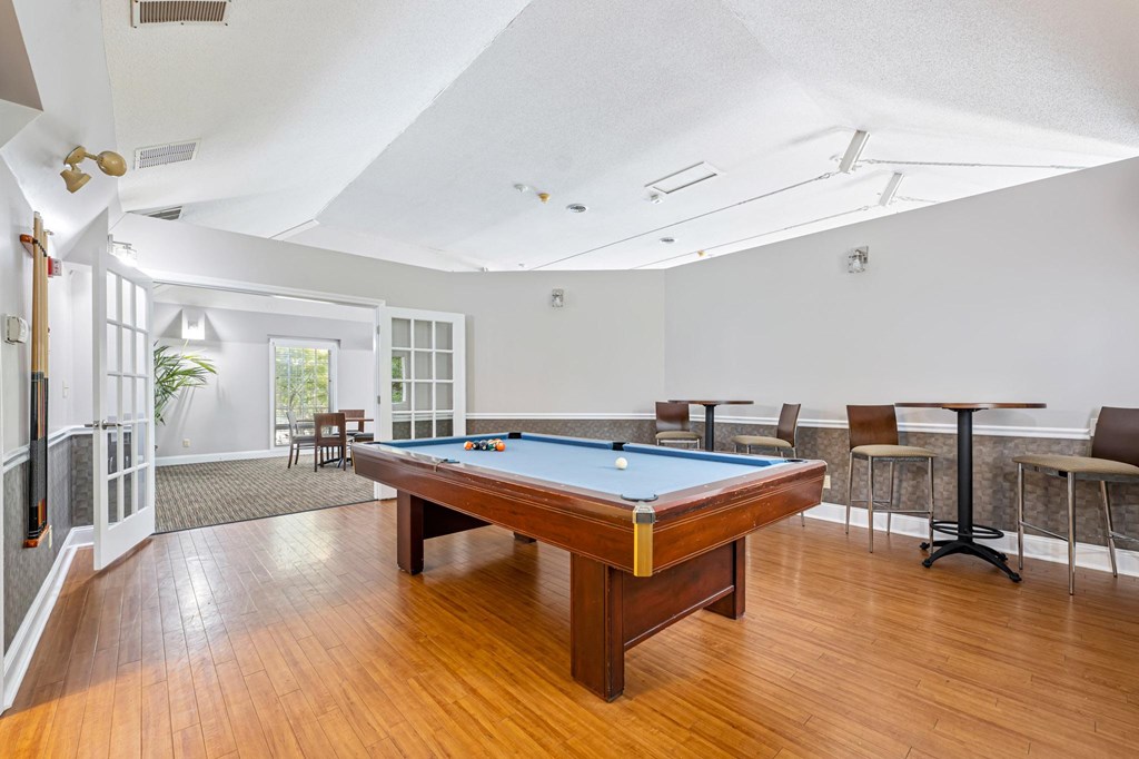 A pool table is in the middle of a room with a high ceiling.