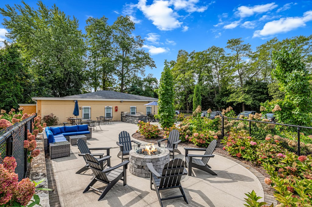 A patio with a fire pit and chairs.