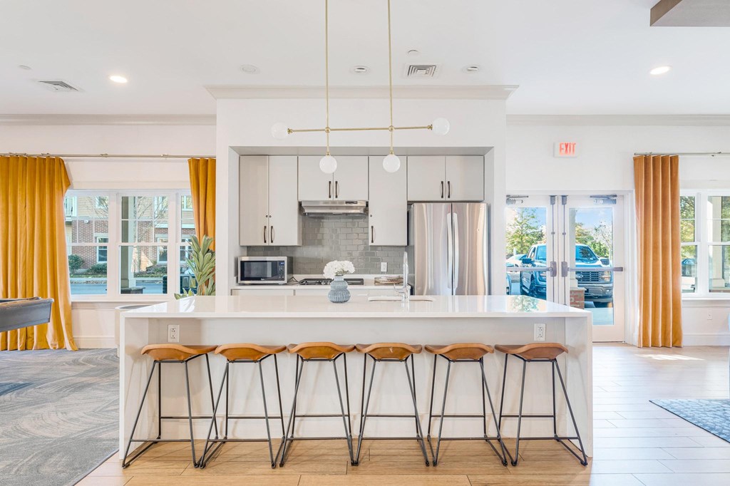 A modern kitchen with a white island and stools.