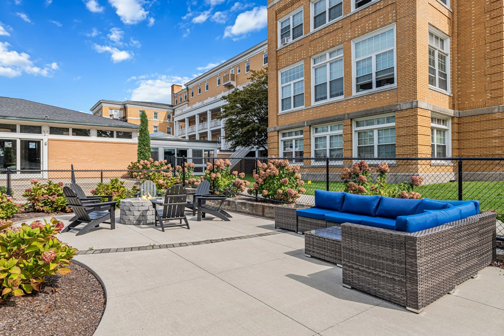 A sunny day at a courtyard with a blue couch and a black fence.