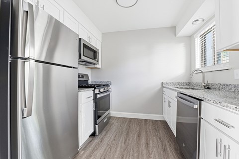 A kitchen with a stainless steel refrigerator and white cabinets.