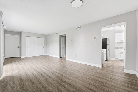 A spacious room with wooden flooring and white walls.