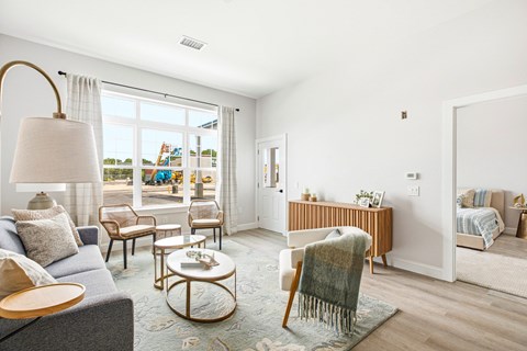 A living room with a grey sofa, a wooden coffee table, and a large window with a view of the outside.