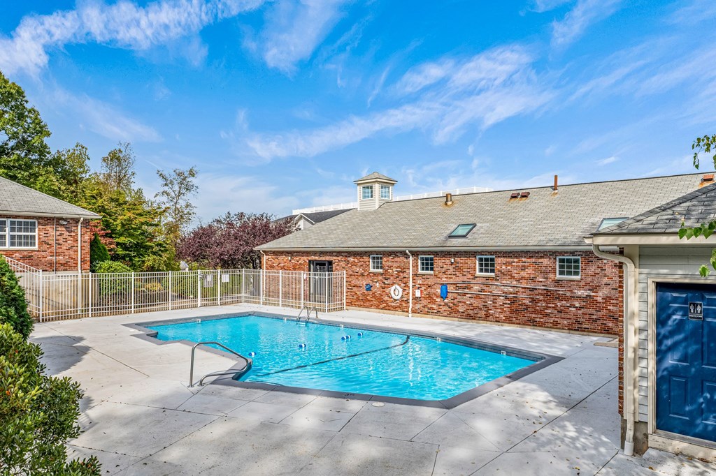 A swimming pool surrounded by a brick wall and a fence.