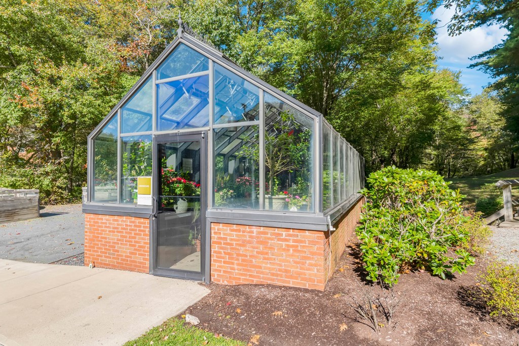 A greenhouse with a brick base and glass panels.