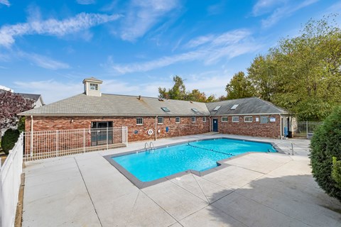 A pool surrounded by a fence and a building in the background.