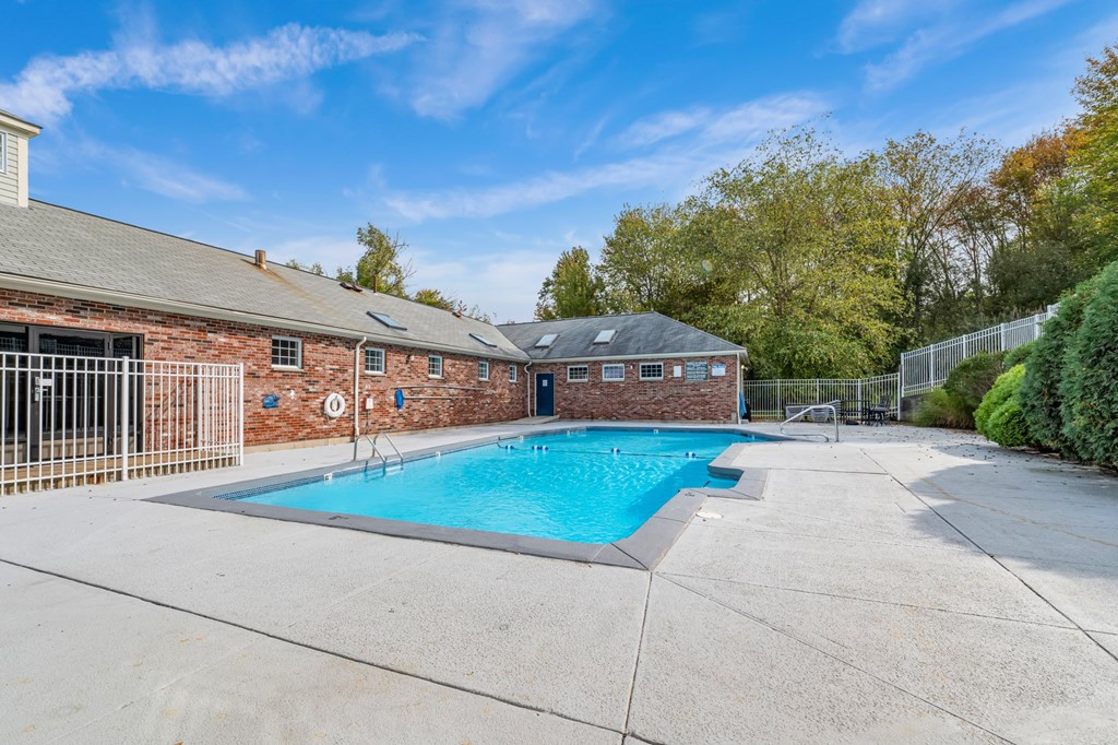 A swimming pool in a backyard with a fence and a building in the background.