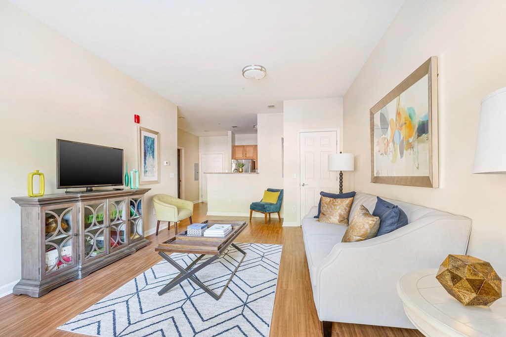 A living room with a white couch and a wooden floor.