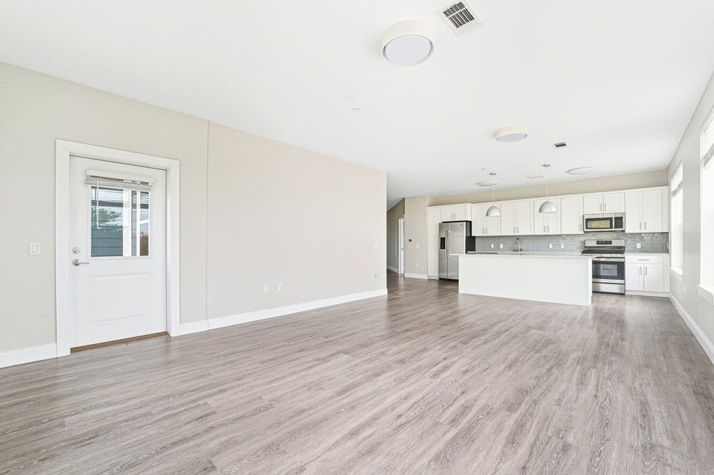 A spacious kitchen with white cabinets and a white door.