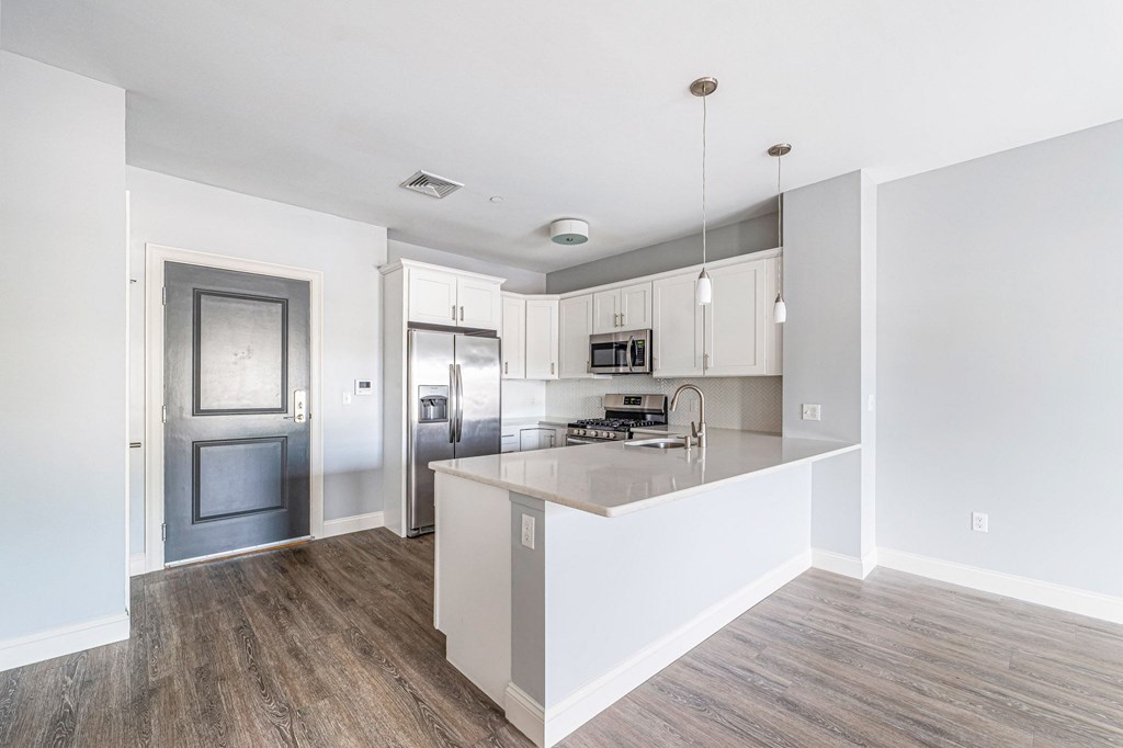 A kitchen with a refrigerator, oven, and cabinets.