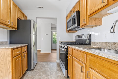 A kitchen with wooden cabinets and a black refrigerator.