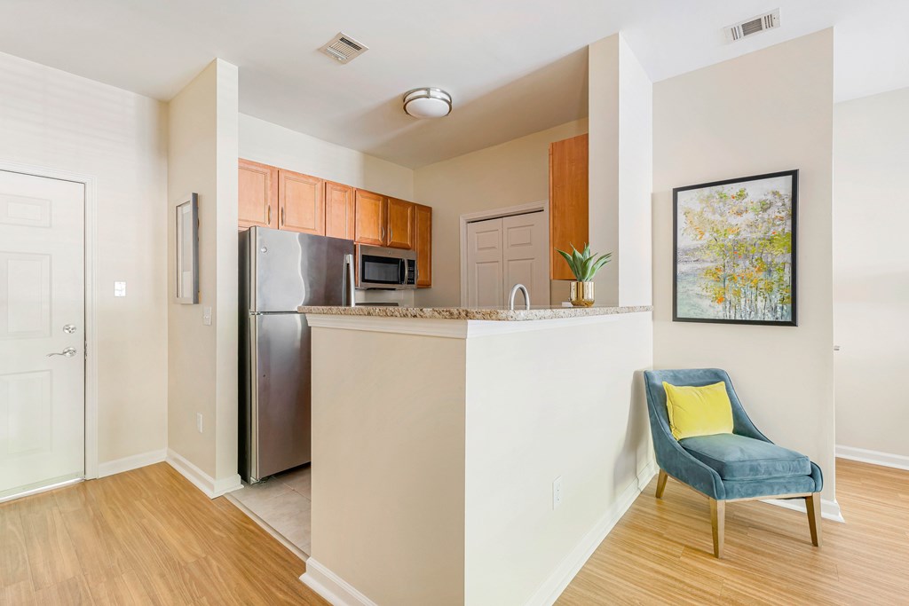 A kitchen with a blue chair and a fridge.