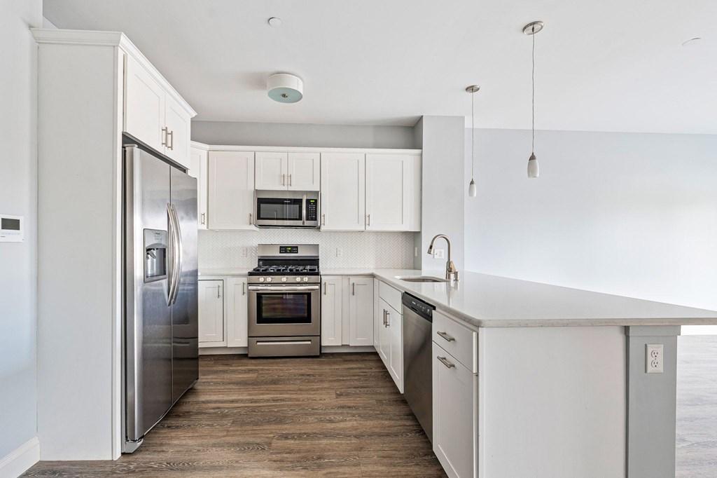 A modern kitchen with white cabinets and stainless steel appliances.