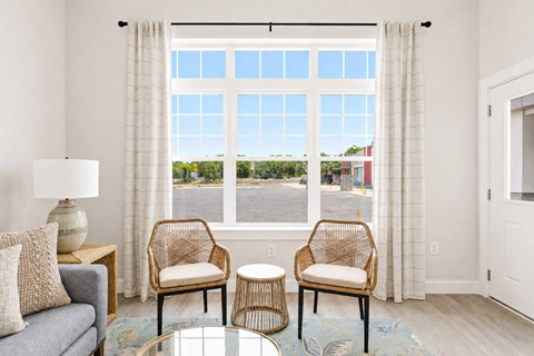 A living room with a grey couch, two chairs and a table.