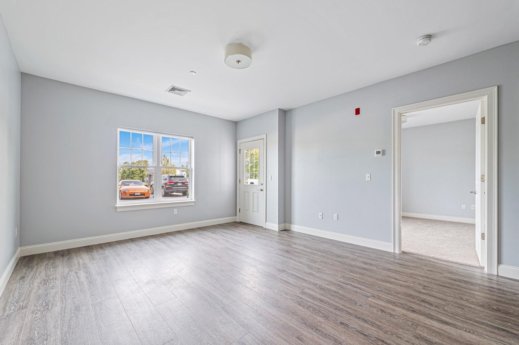 A spacious room with a large window and a framed picture on the wall.