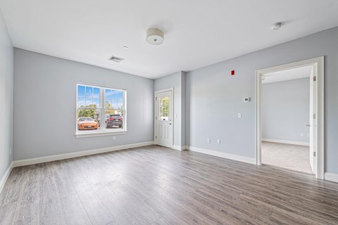 A spacious room with a large window and a framed picture on the wall.