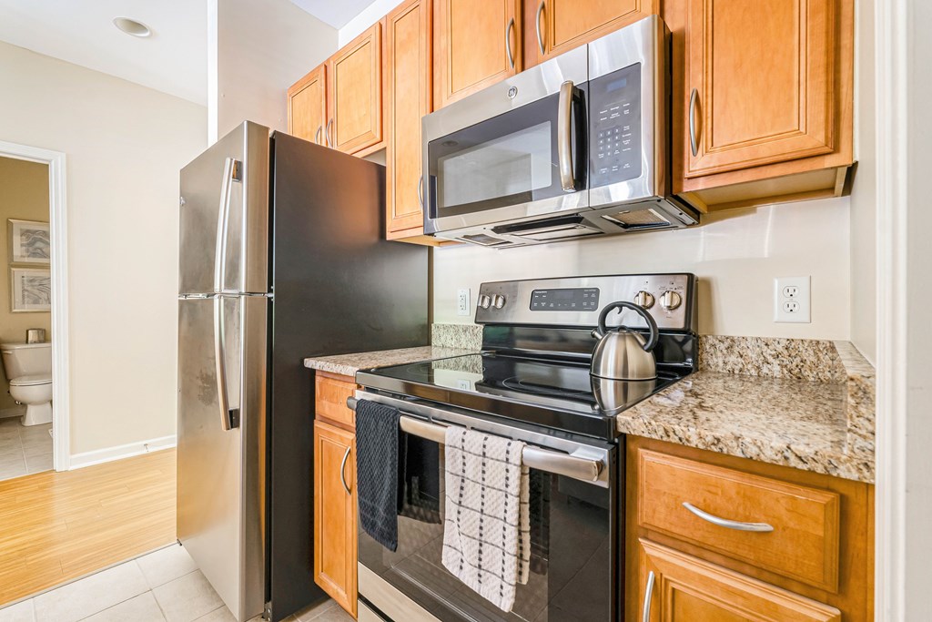 A kitchen with a black refrigerator, black oven, and a black microwave.
