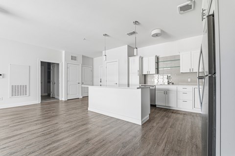 A kitchen with white cabinets and a wooden floor.