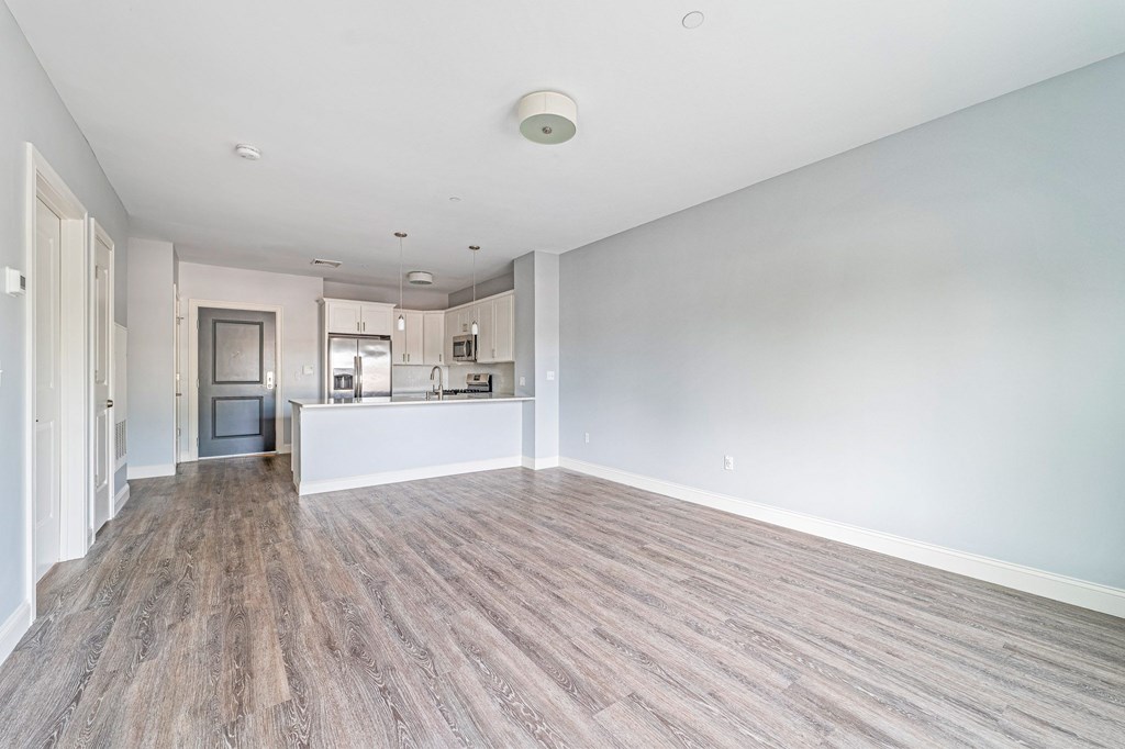 A spacious room with wooden flooring and white walls.