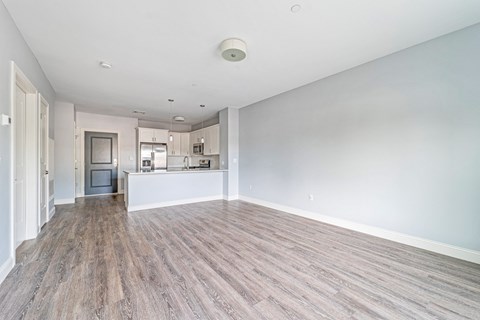 A spacious room with wooden flooring and white walls.