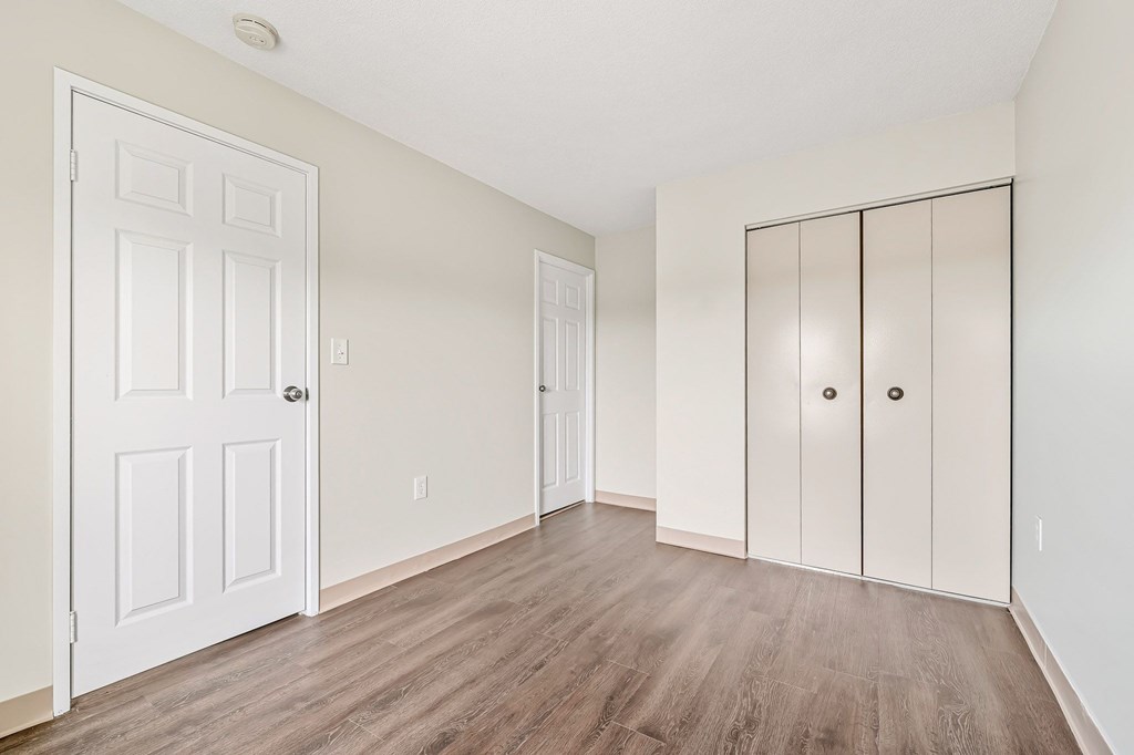 A room with a white door and a white cabinet with two doors.