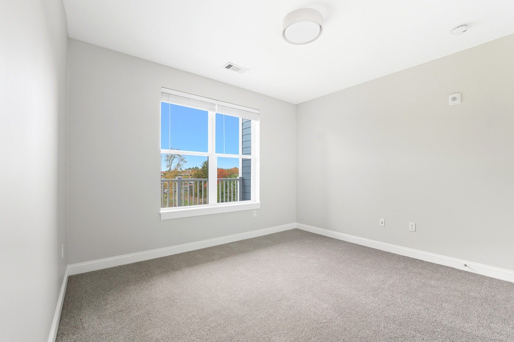 A room with a window and a carpeted floor.
