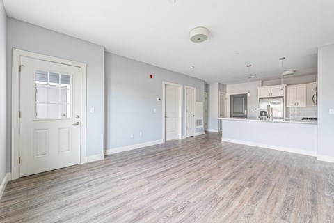 A large empty room with wooden flooring and white walls.