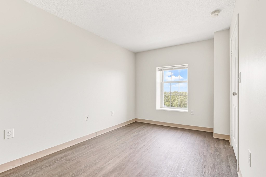 A room with a window and wooden flooring.