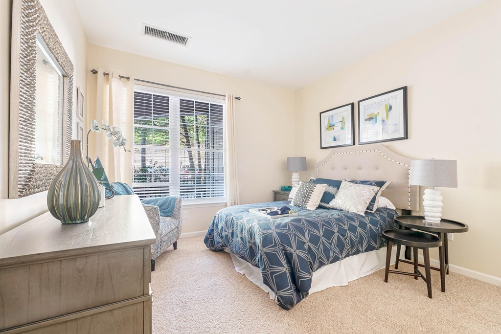 A bedroom with a bed, nightstand, and a dresser.