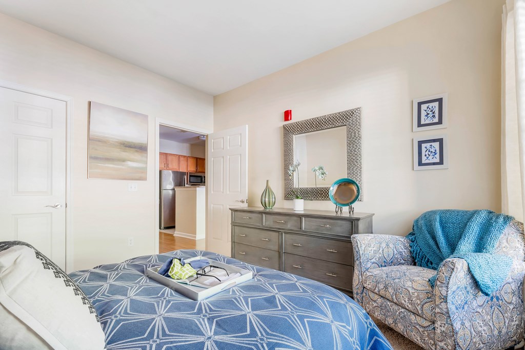 A bedroom with a blue patterned bedspread and a grey sofa.