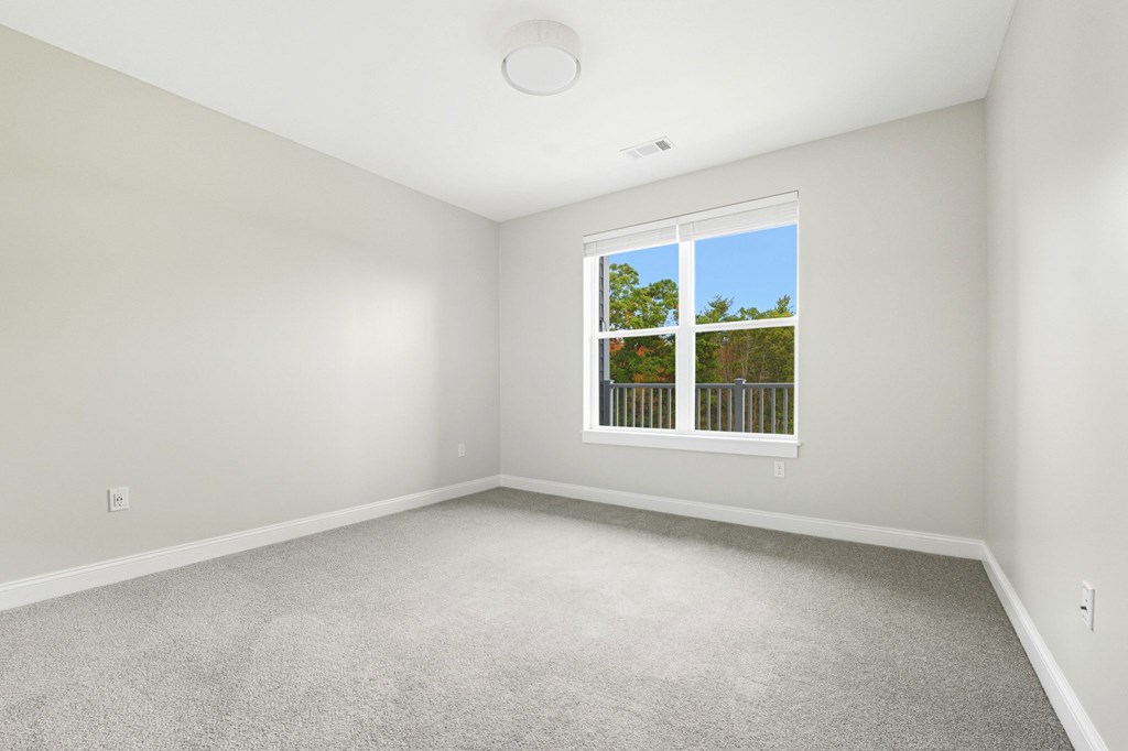 A room with a window and a carpeted floor.