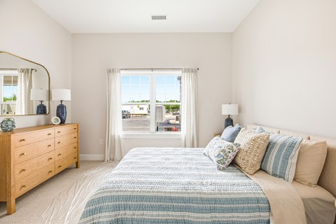 A bedroom with a large bed and a dresser with a mirror.