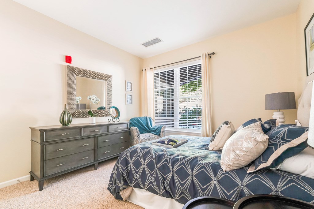 A bedroom with a bed, dresser, and mirror.