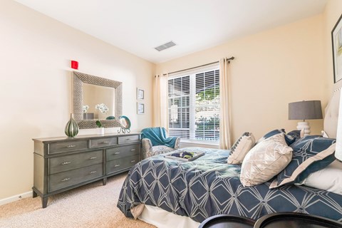 A bedroom with a bed, dresser, and mirror.