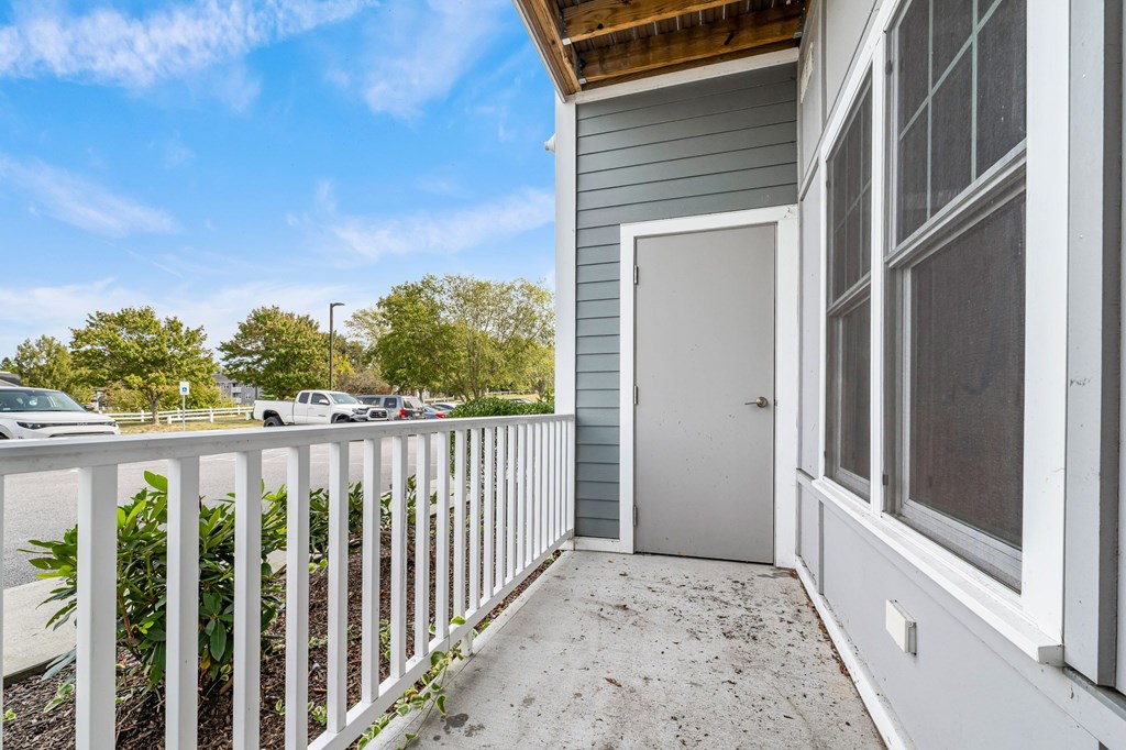 A white fence leads to a grey door on a house.