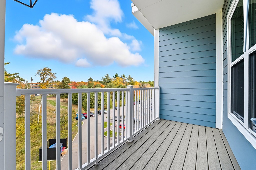 A balcony with a view of a road and trees.