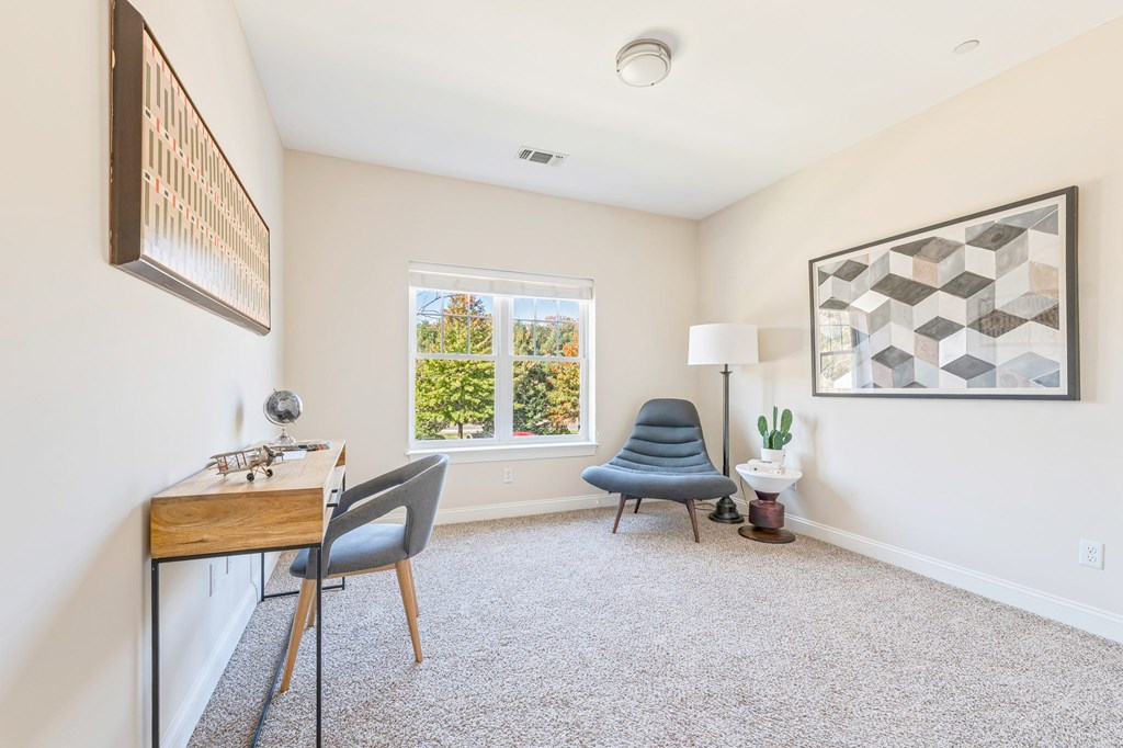 A room with a desk, chair, and a window overlooking a tree.