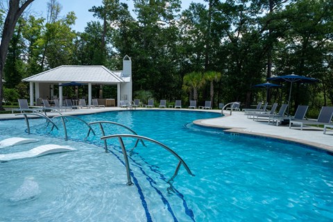 A pool with a diving board and a pavilion in the background.