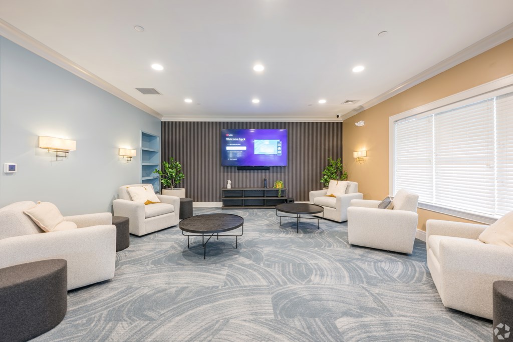 A spacious waiting room with a TV screen, comfortable seating, and a coffee table at Axis at Lakeshore Apartments, Bridgewater, 02324