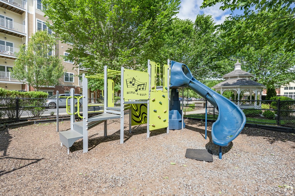 A playground with a blue slide and a yellow climbing frame at Axis at Lakeshore Apartments, Bridgewater, 02324