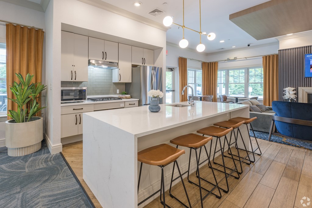 A modern kitchen with a white island and wooden stools at Axis at Lakeshore Apartments, Bridgewater, Massachusetts