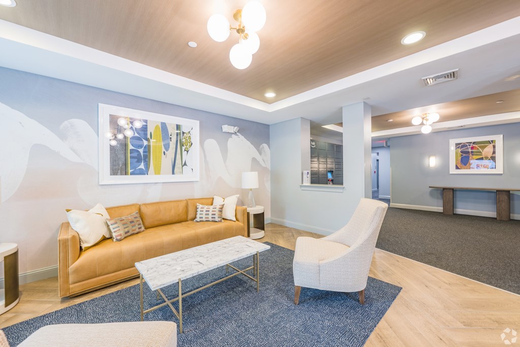 A living room with a sofa, a chair, and a coffee table at Axis at Lakeshore Apartments, Bridgewater, 02324