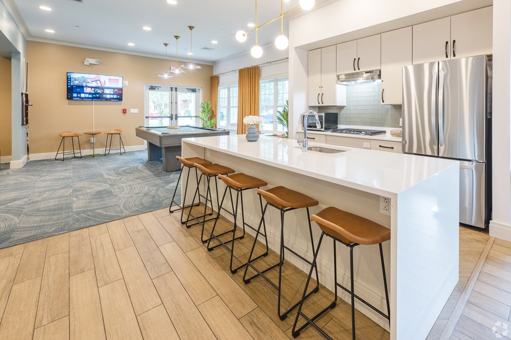 A modern kitchen with a long white counter and bar stools at Axis at Lakeshore Apartments, Bridgewater, Massachusetts, 02324