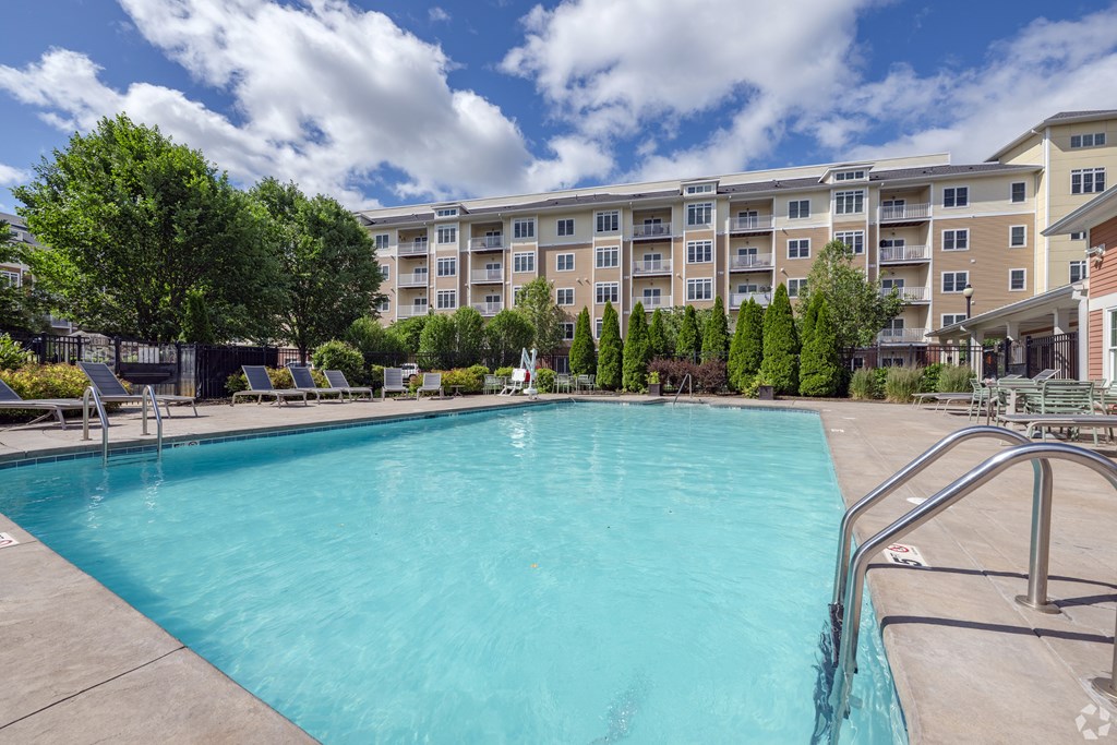 A swimming pool in front of a large apartment building at Axis at Lakeshore Apartments, Bridgewater, 02324