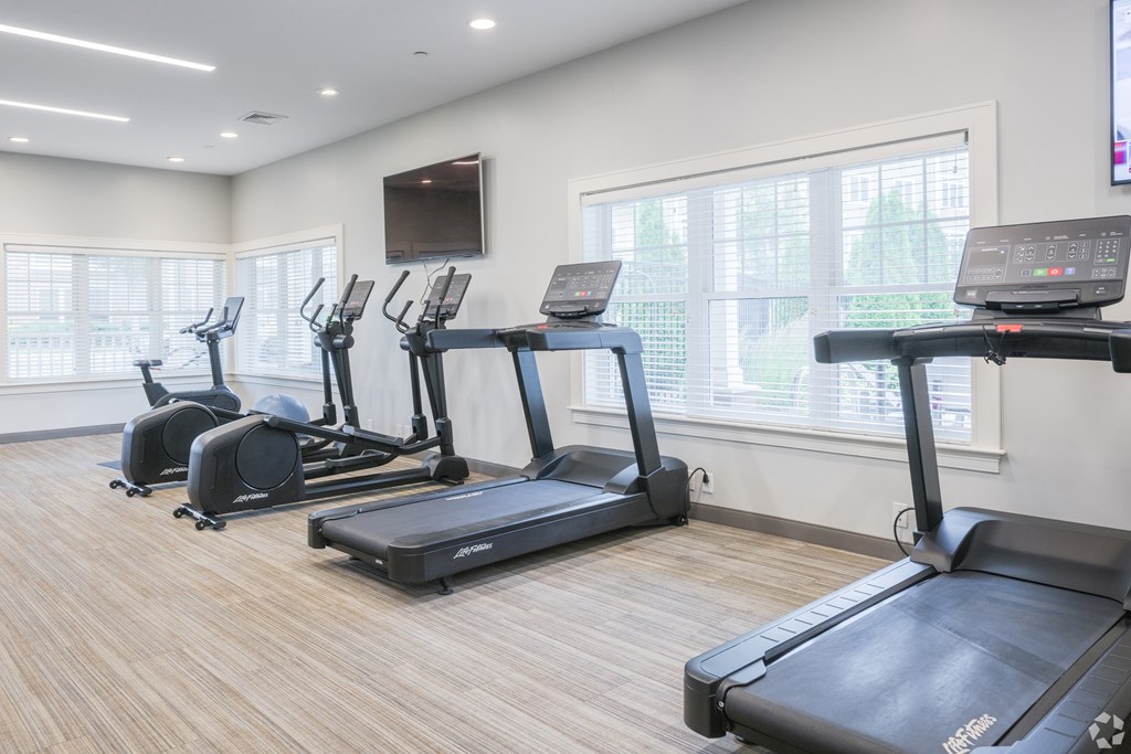 A gym with treadmills and a television mounted on the wall at Axis at Lakeshore Apartments, Bridgewater, 02324